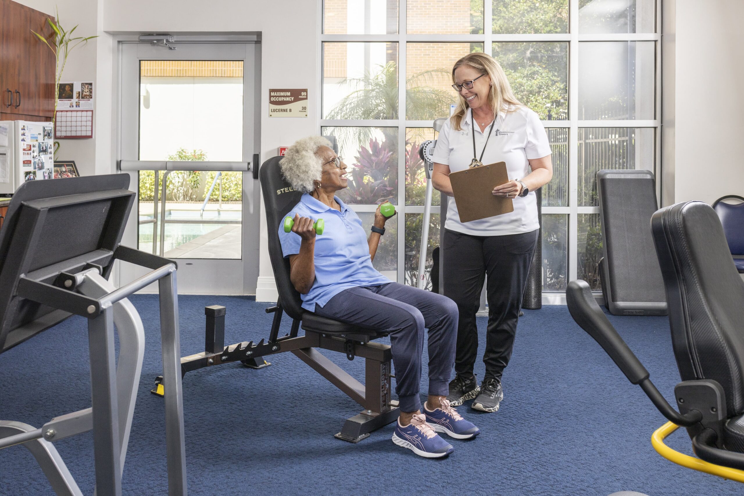 Resident exercising with a staff member in the fitness area