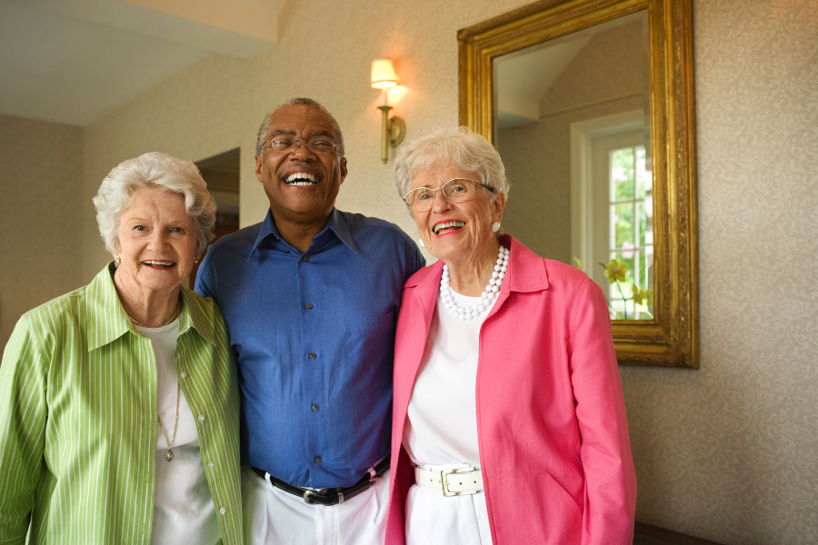 Three residents smiling in a well-lit common area