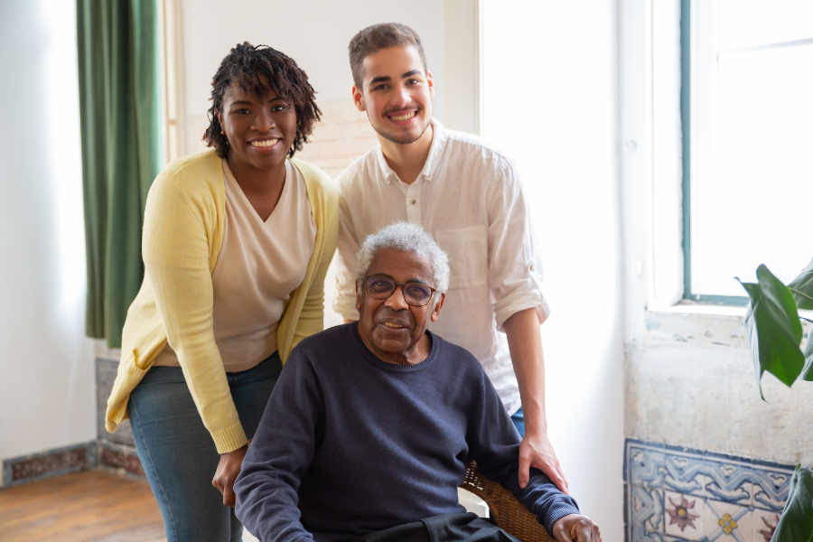 A young man and woman with an elderly resident in a bright interior