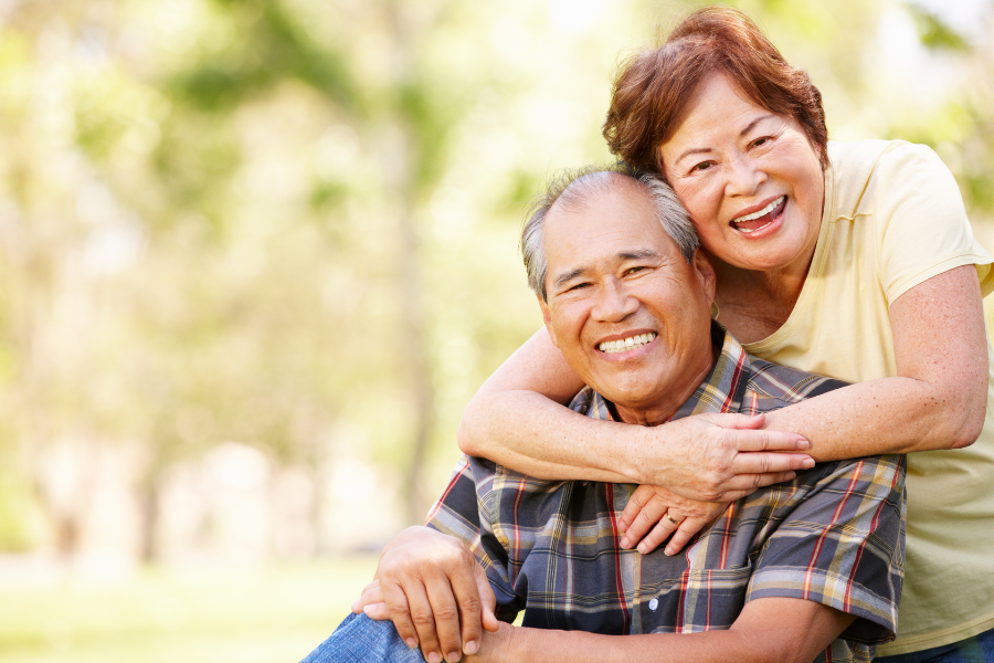 Elderly couple smiling outdoors in a park setting