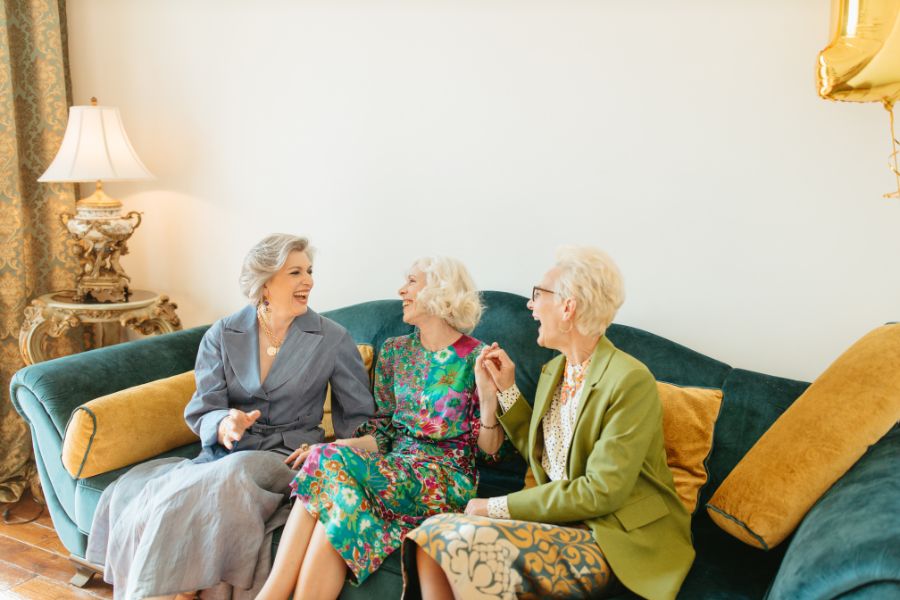 Three smiling women enjoying a conversation on a couch