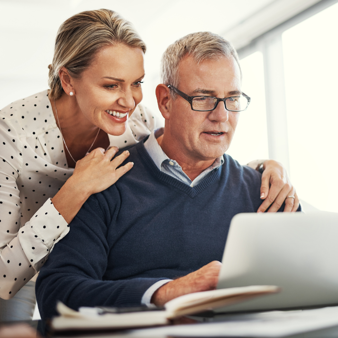 A woman assisting a senior man with a laptop