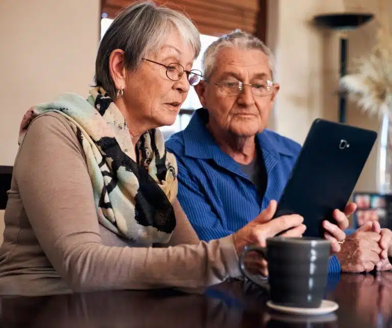 Two seniors engaging with a tablet at a table