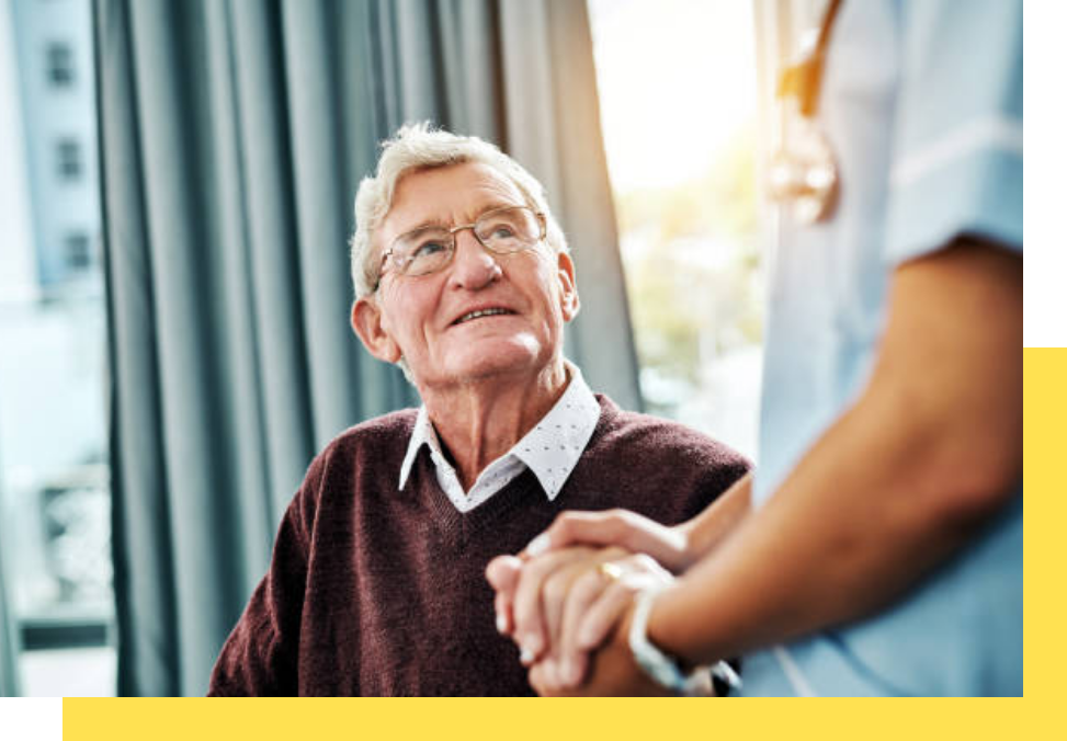 A senior resident interacting with a caregiver in a sunny room
