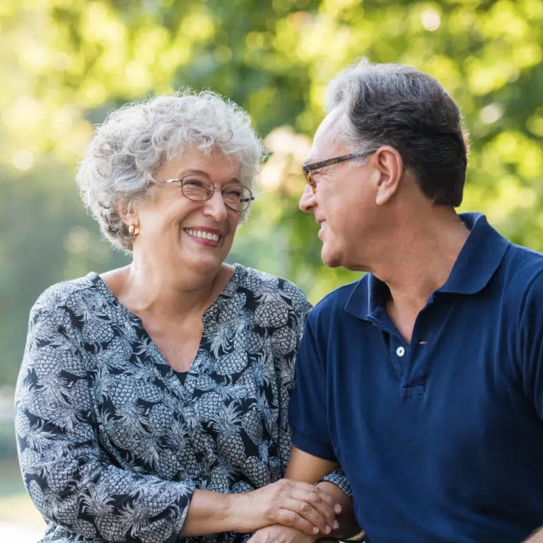 Two seniors smiling together in an outdoor setting