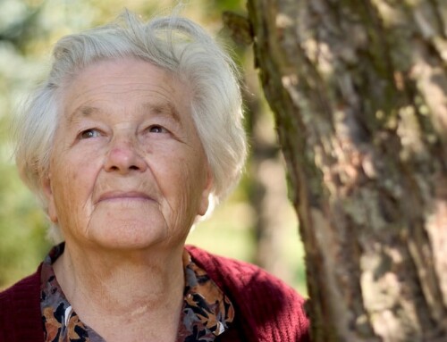 Elderly woman enjoying nature near a tree