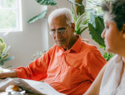 Elderly man reading a newspaper at a table
