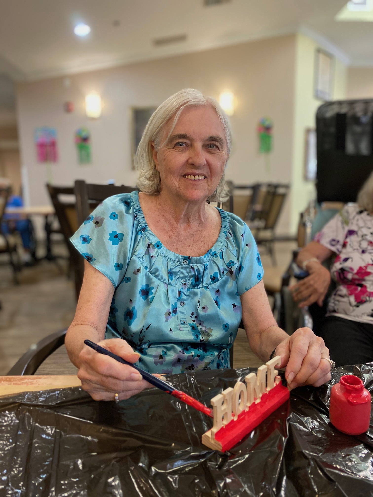 Resident painting a wooden decoration in an activity room