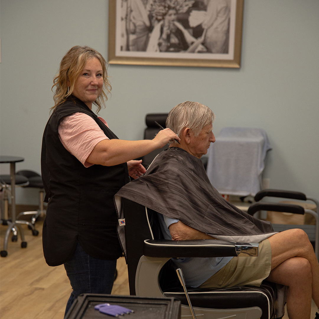 Stylist cutting hair for a resident in the salon