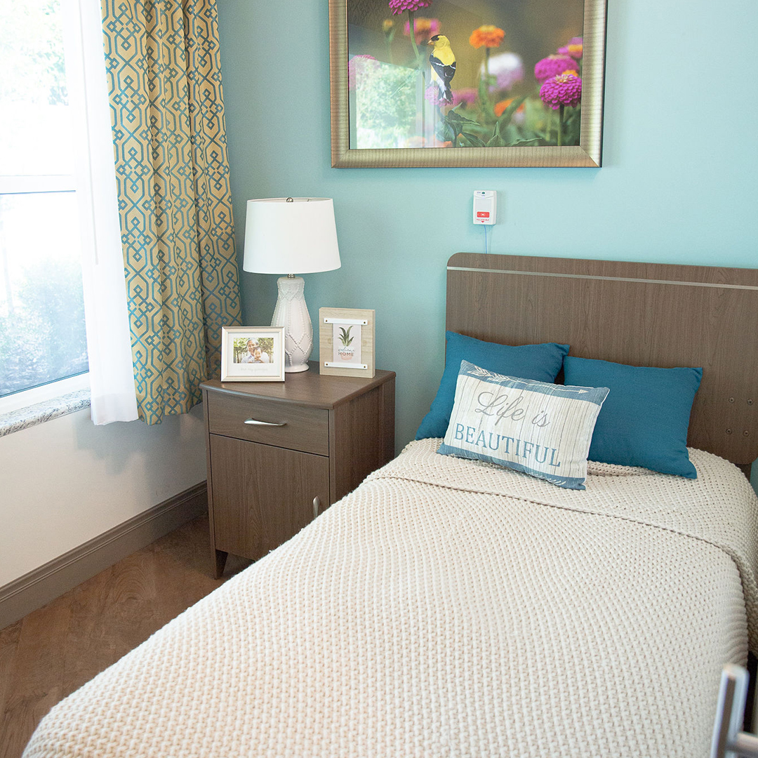 A cozy resident room with decorated bed and light