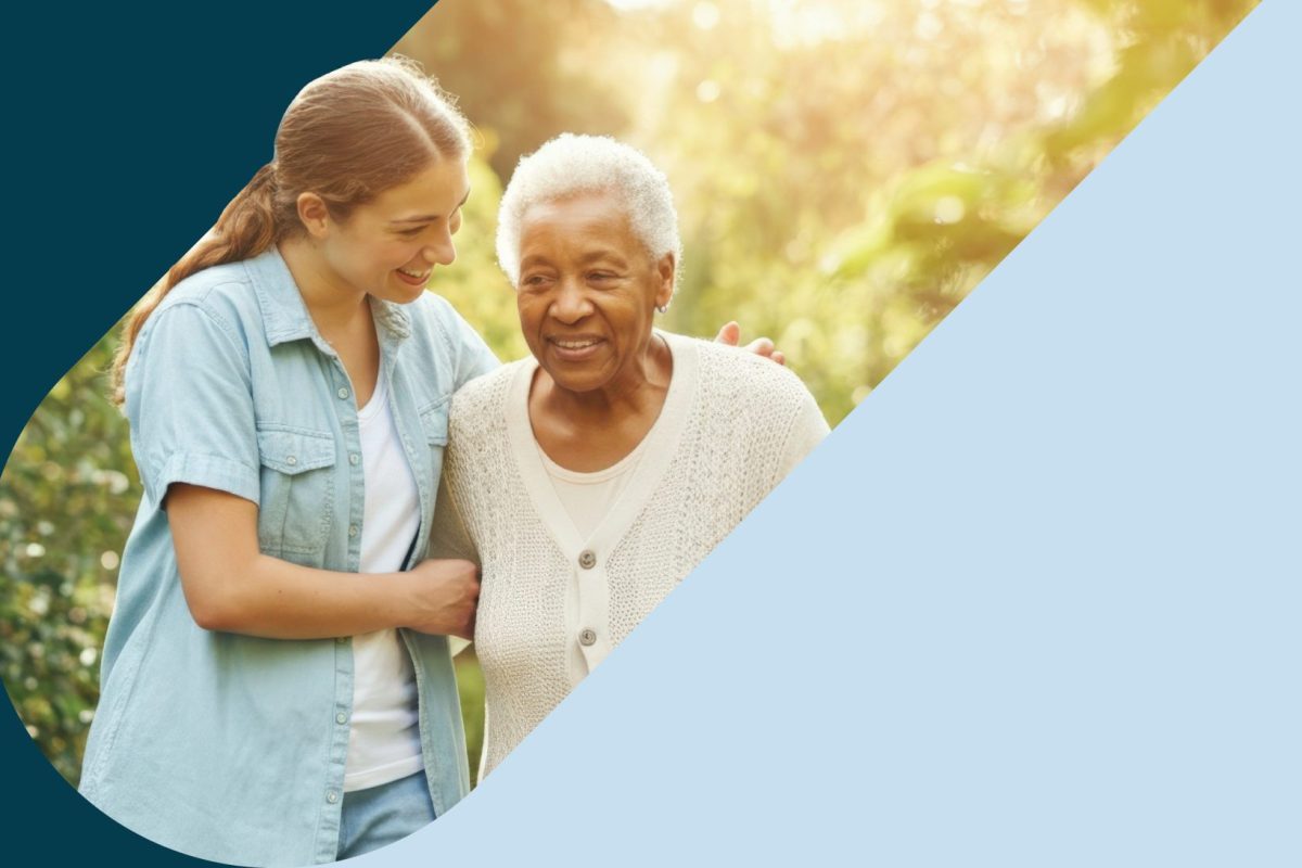 A senior woman walking outdoors with a caregiver