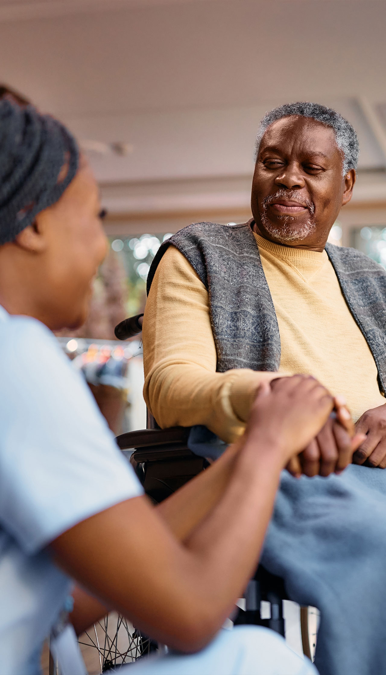 Caregiver holding hands with resident in a cozy interior