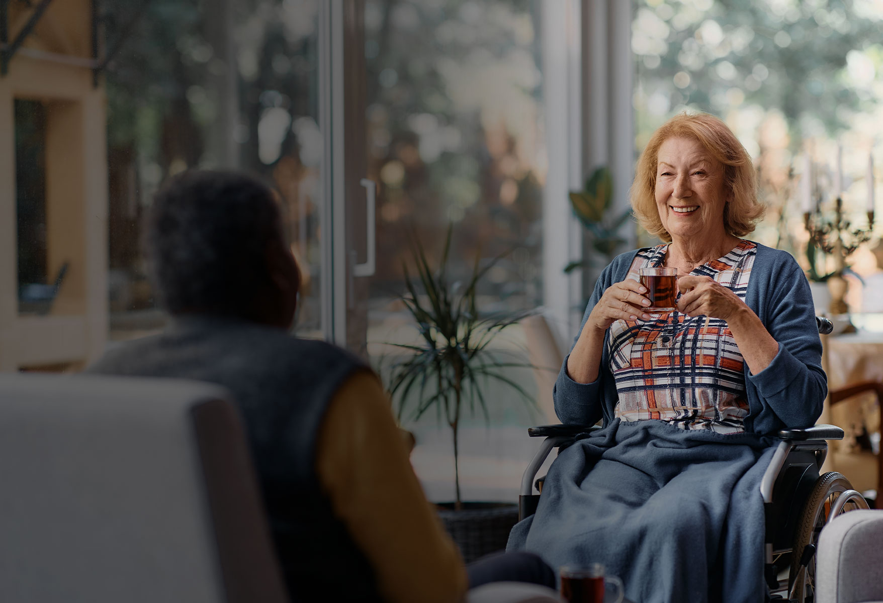 Resident smiling and holding a cup in a common area
