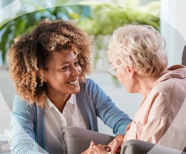 Caregiver smiling with a senior resident indoors.