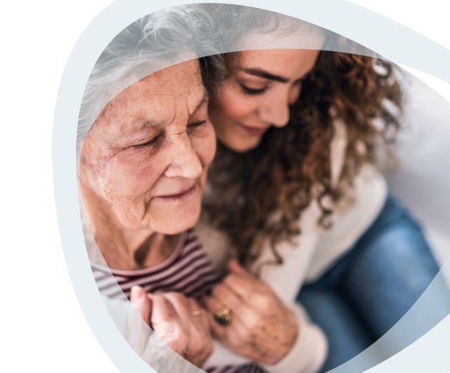 A caregiver embracing an elderly woman.