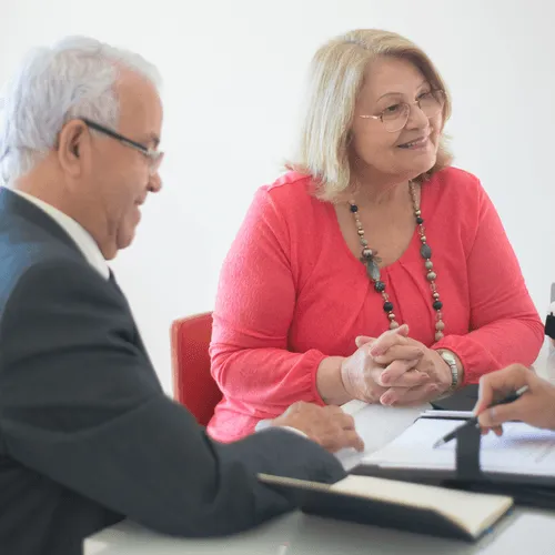 Two seniors engaged in conversation during a meeting.