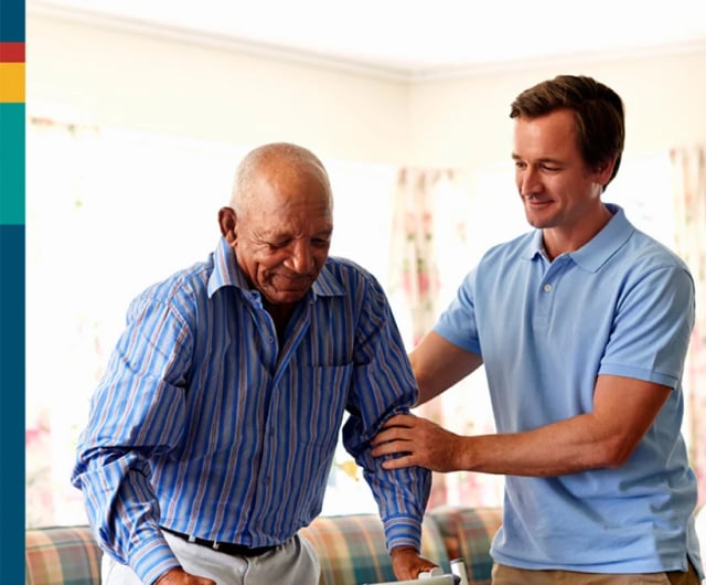 Caregiver assisting a senior man in an interior setting