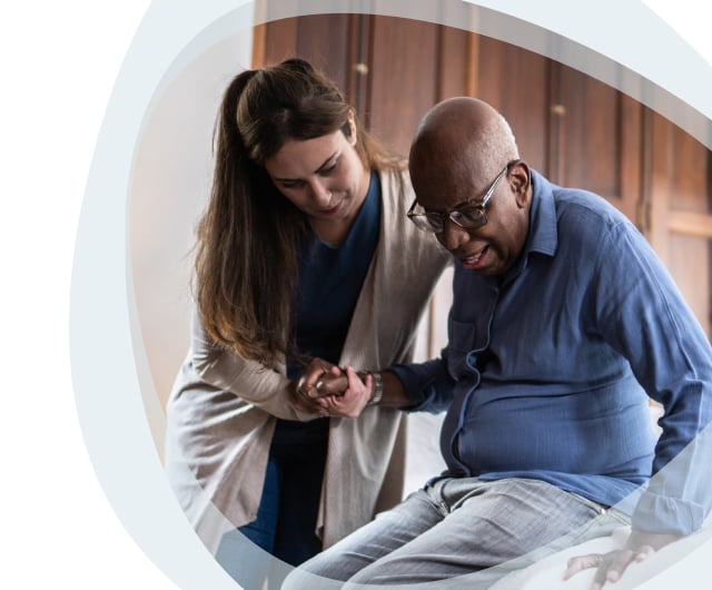 Caregiver assisting an elderly man in a room