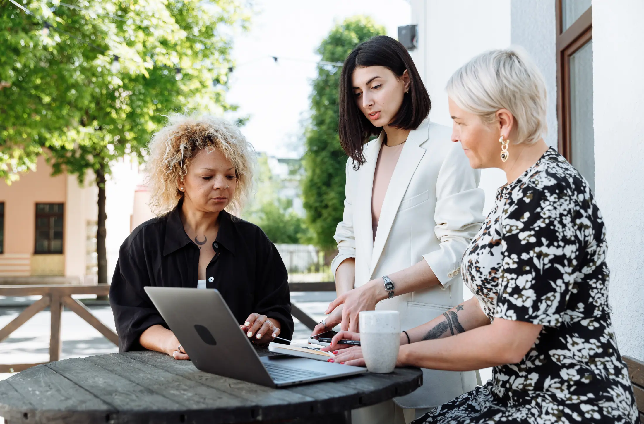 Three women collaborating at an outdoor table
