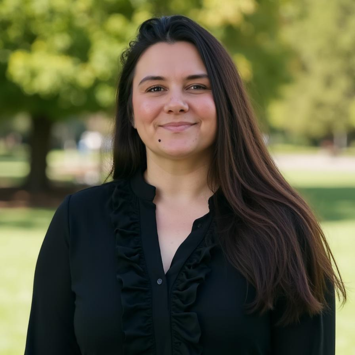 Portrait of a woman smiling in a park setting.