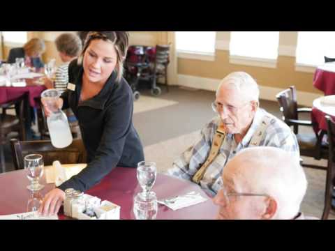 Staff serving food to residents in a dining area