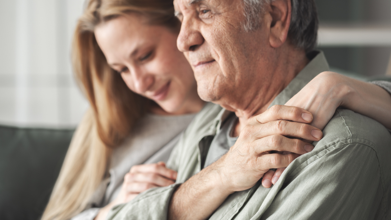 A woman embracing an older man, showing affection and support.