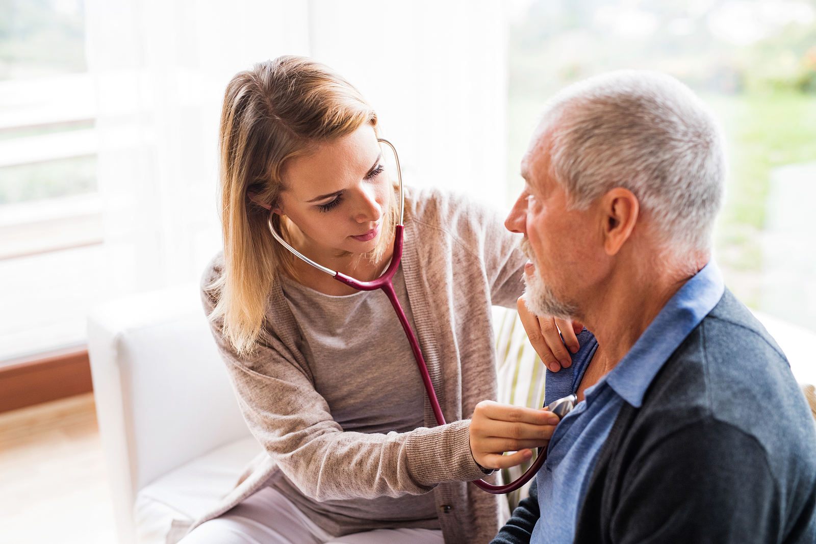 Healthcare professional examining a senior resident in a bright room