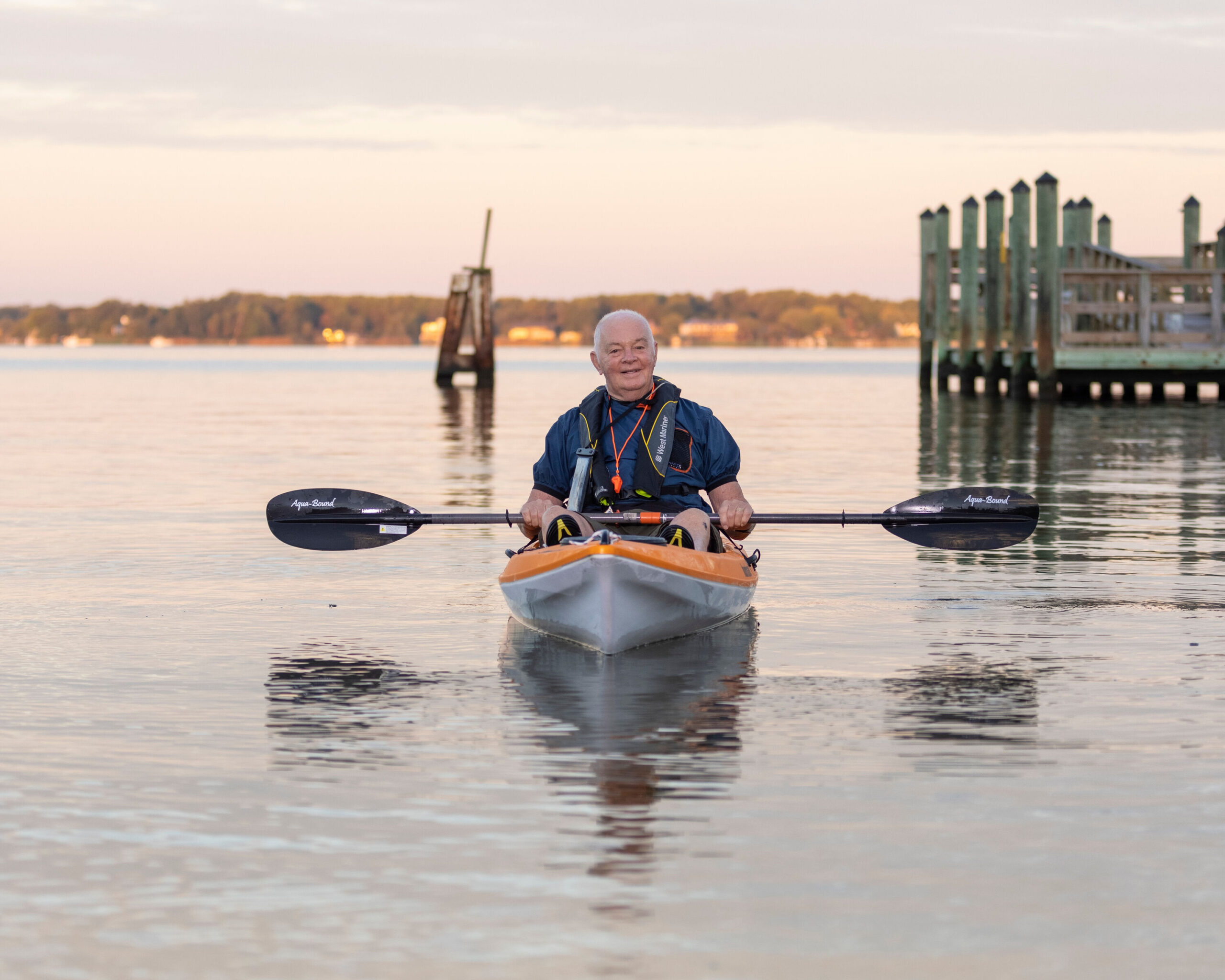 An elderly man kayaking on calm waters