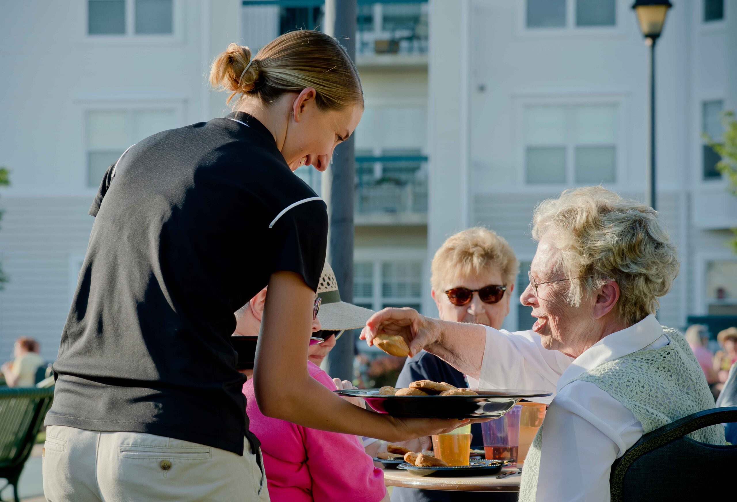 Staff serving a meal to a resident in an outdoor setting