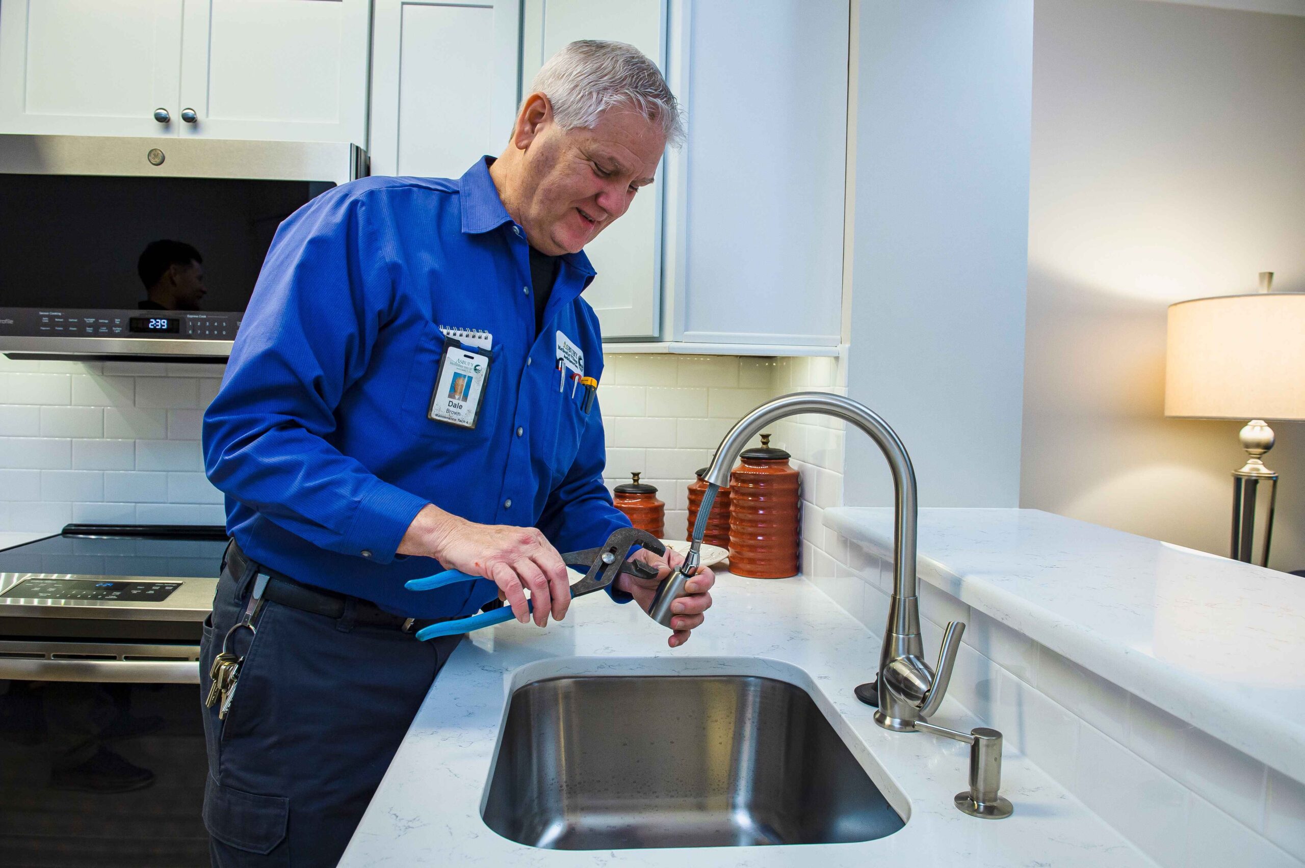 Maintenance staff repairing a sink in the kitchen