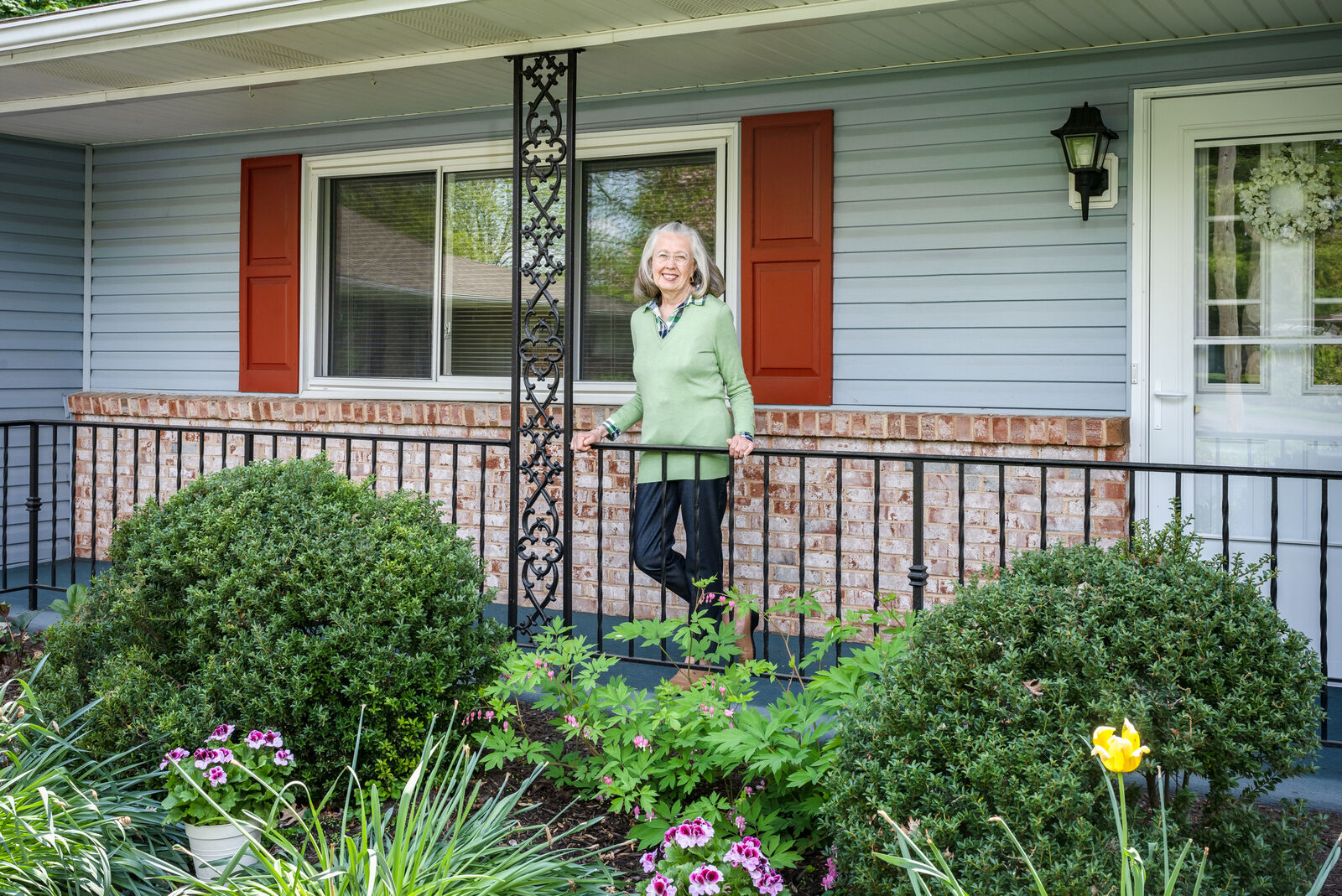 Resident smiling on the front porch surrounded by flowers