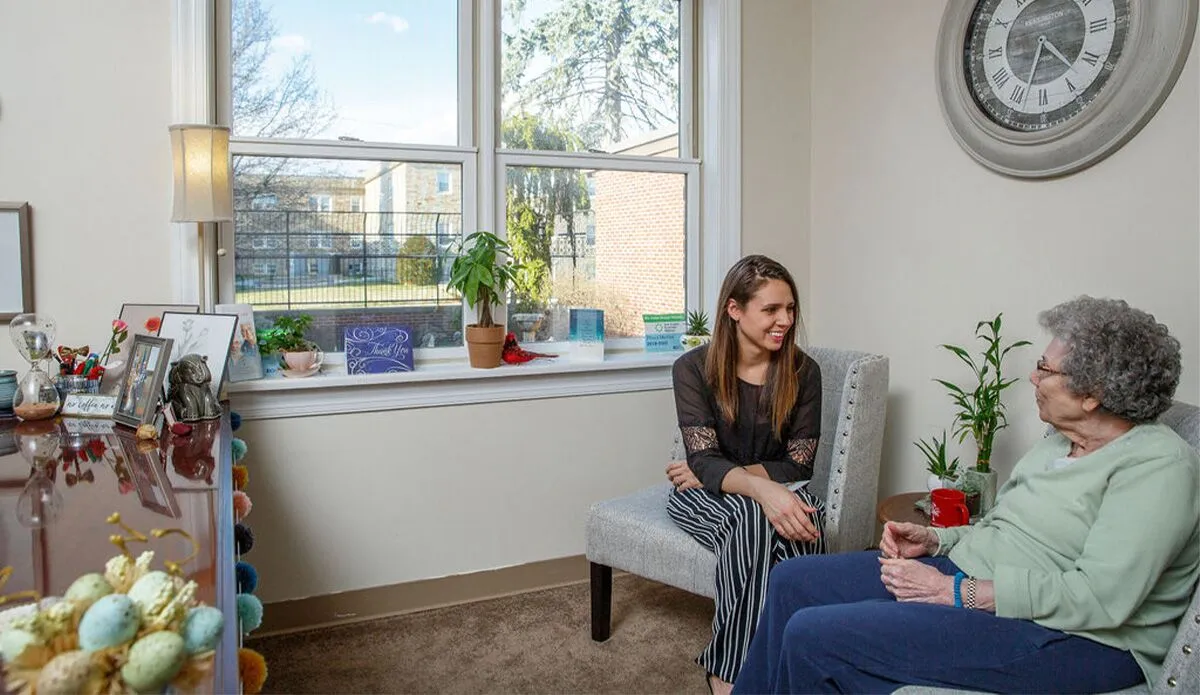 A resident and staff member in a cozy common area