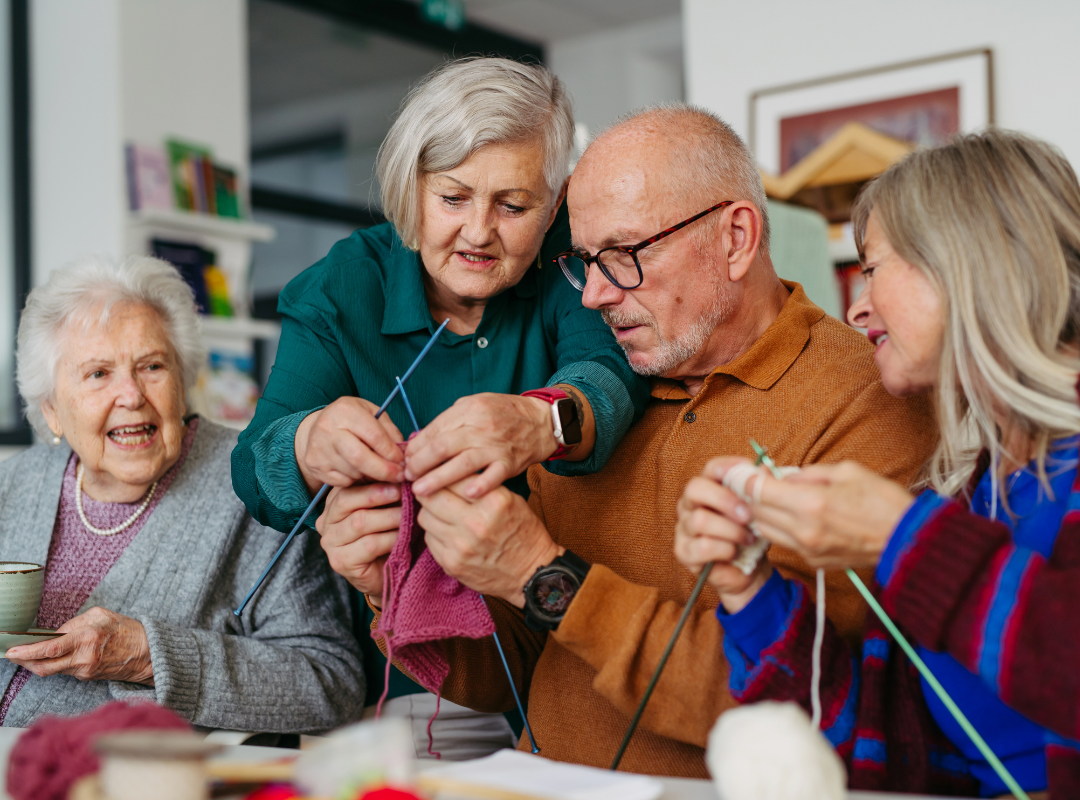 Residents participating in a knitting activity with staff assist