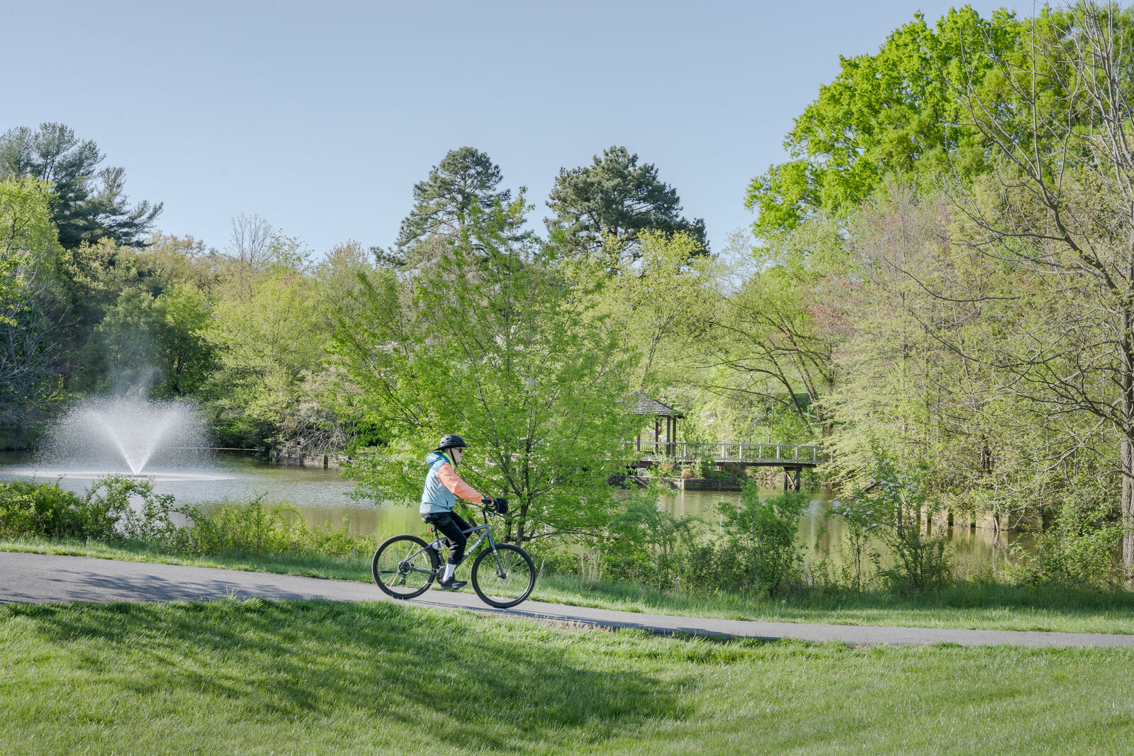 Resident biking along a path by a pond