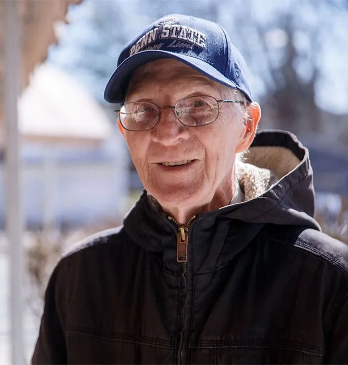 A smiling resident wearing a cap in a casual outdoor setting
