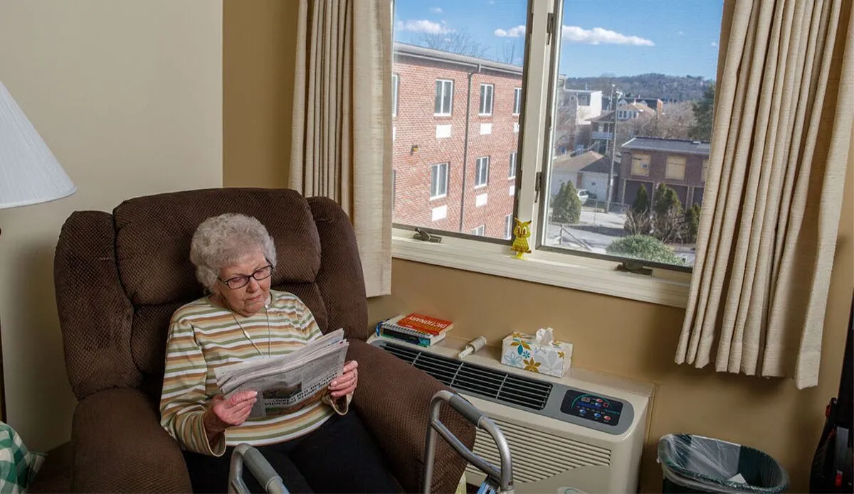 Elderly woman reading a newspaper in her room