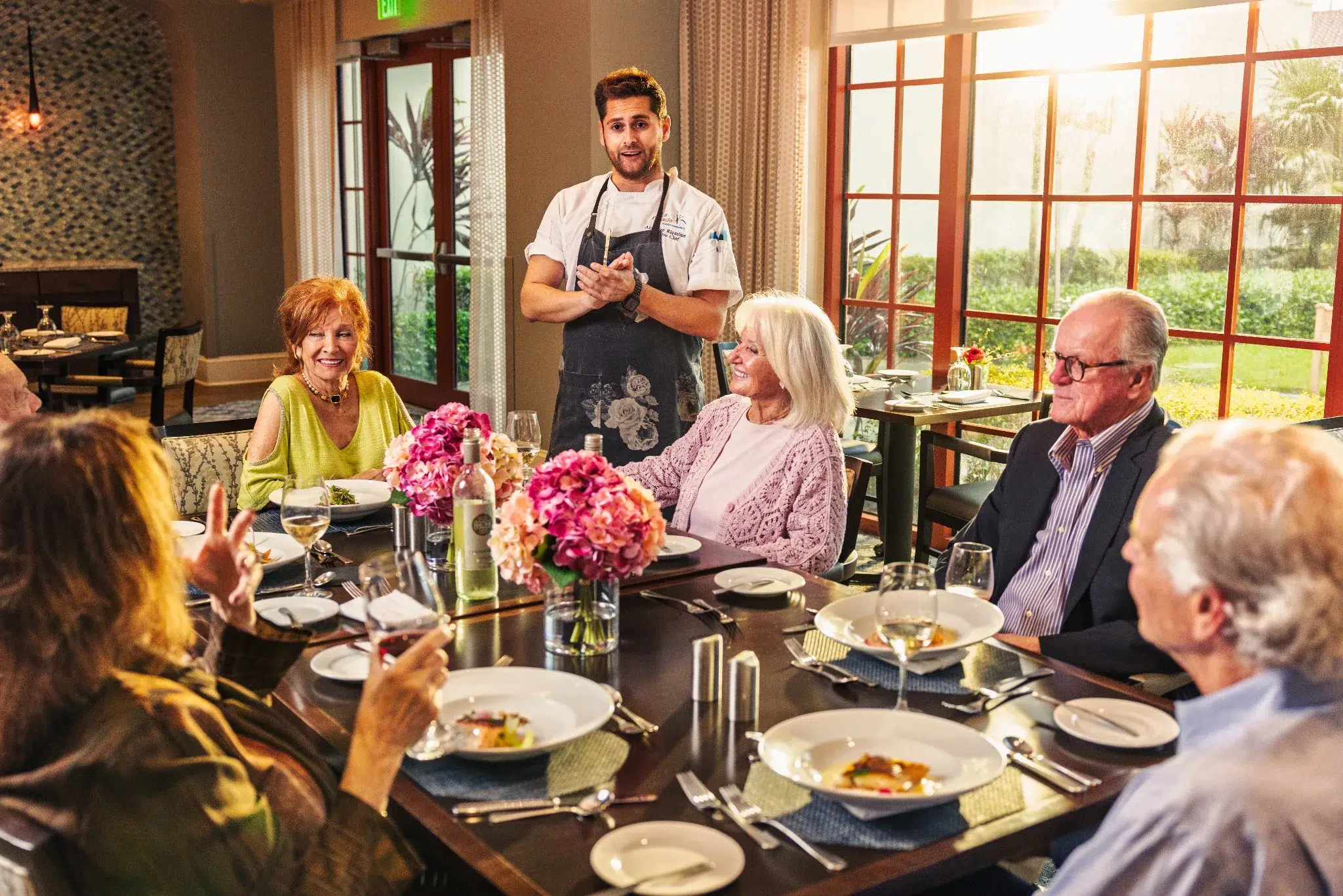 Residents enjoying a meal in the dining room with a chef