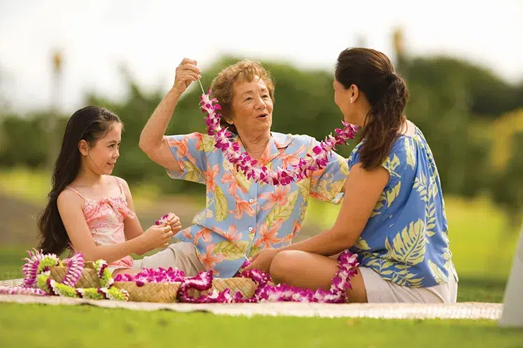 Residents making flower leis outdoors