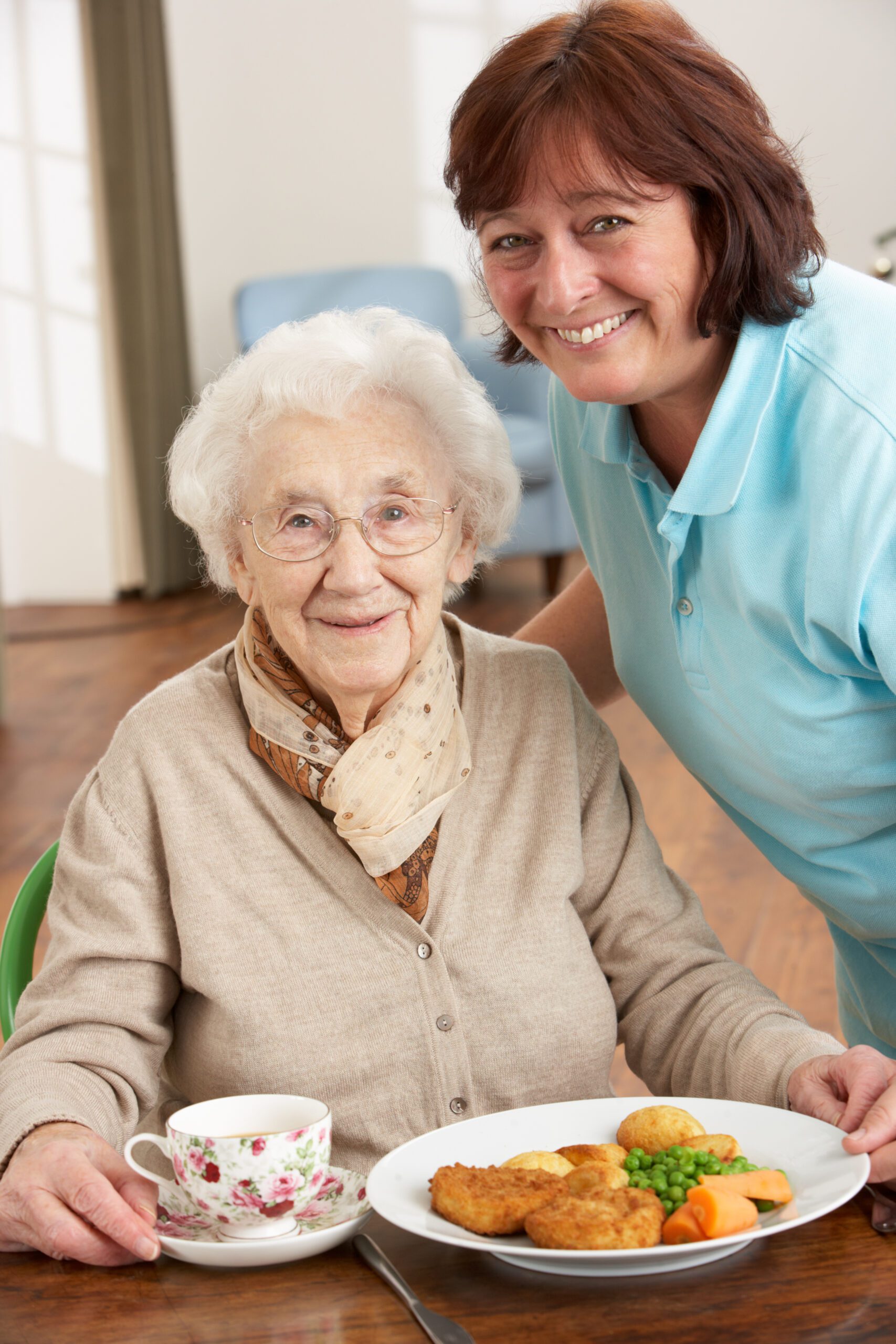 Senior resident enjoying a meal with staff member.