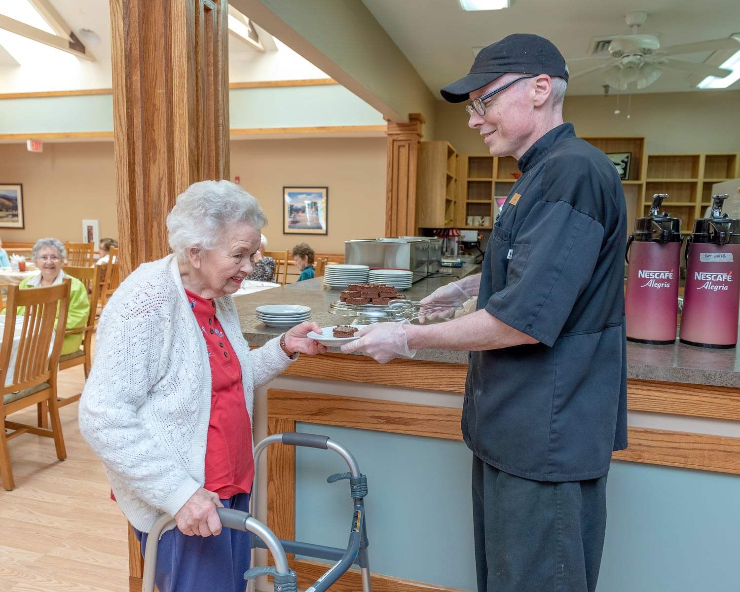 Staff serving food to a resident in the dining area