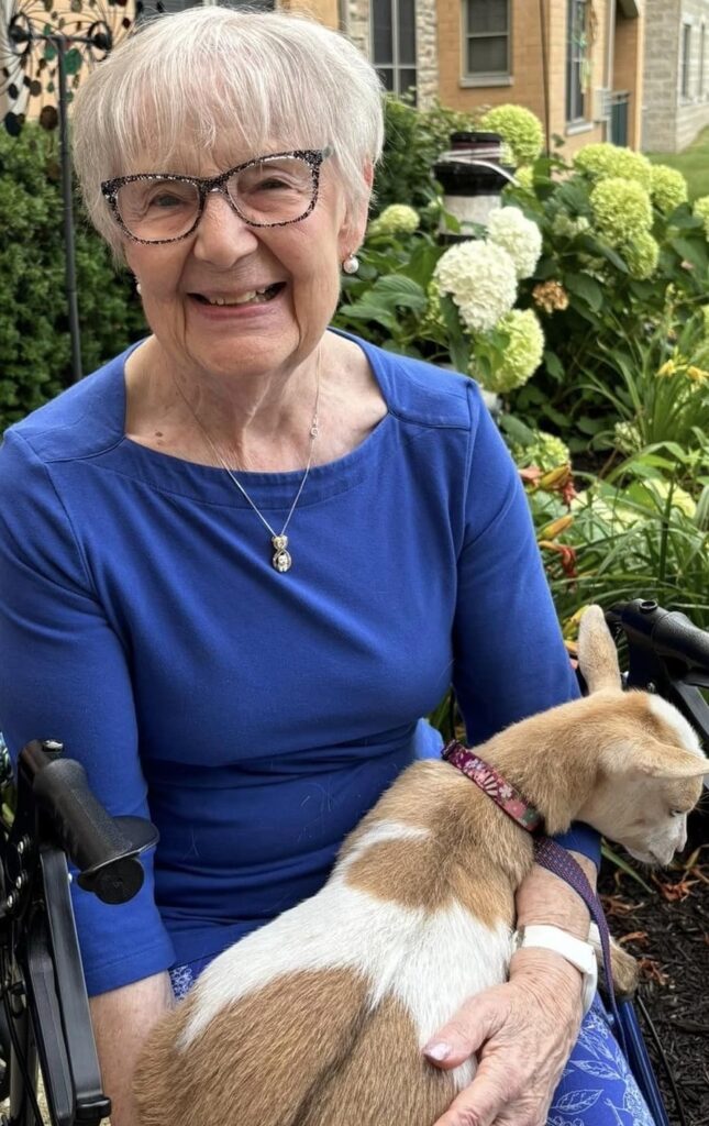 Senior woman smiling with a dog in a garden