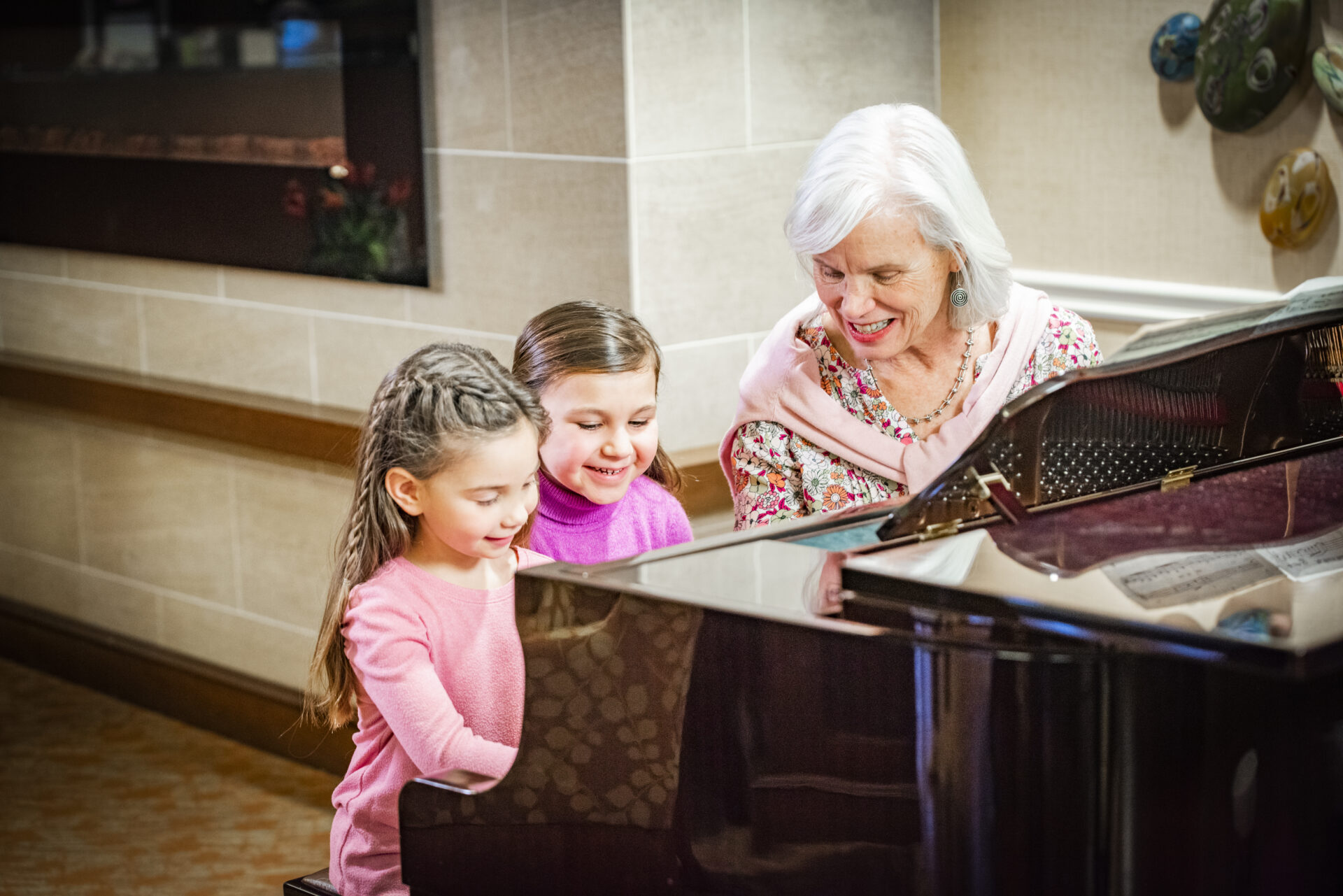 Residents enjoying music with two children at a piano.