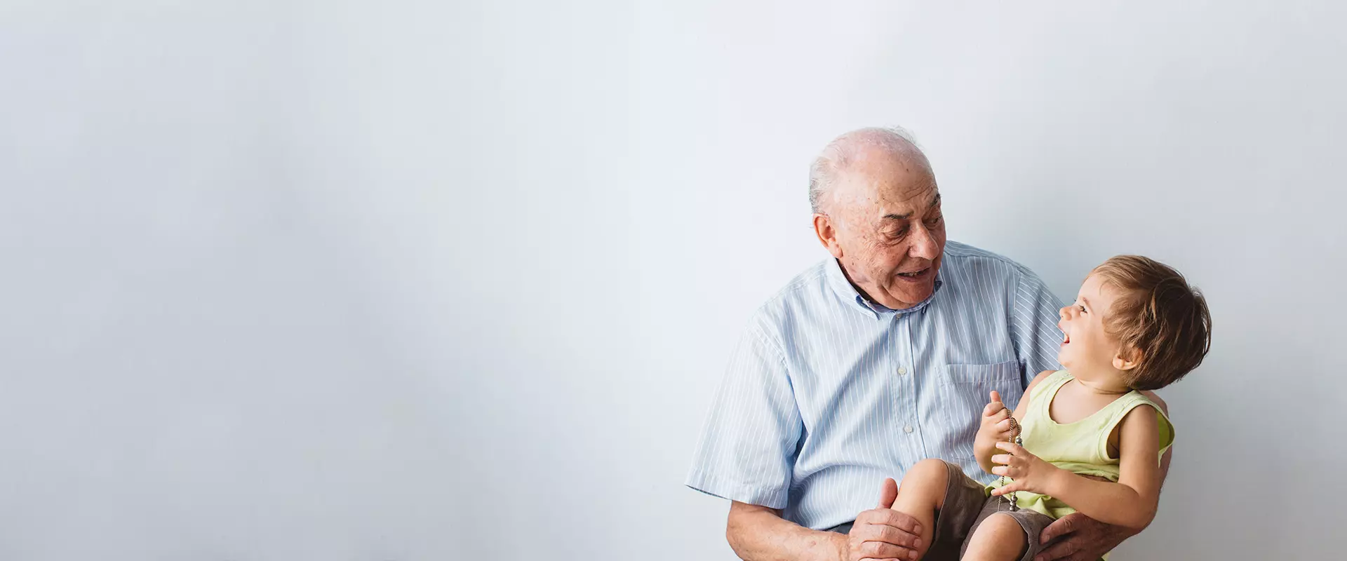 An elderly man laughing with a young child.
