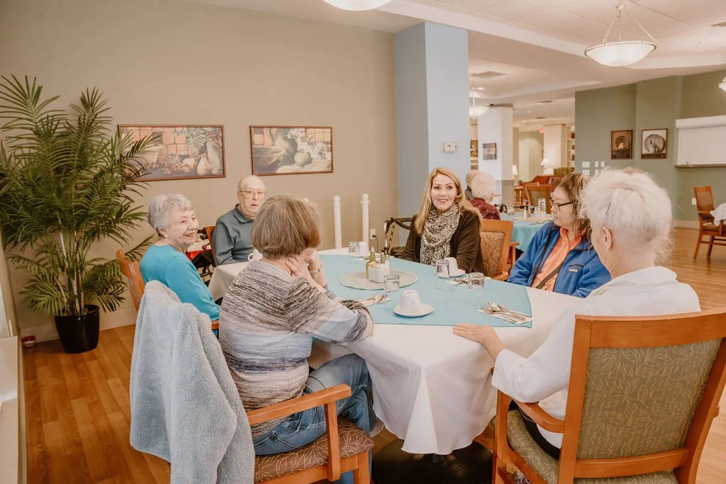 Residents and staff enjoying conversation in a dining area.