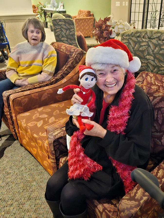Residents celebrating with a doll in a common area.