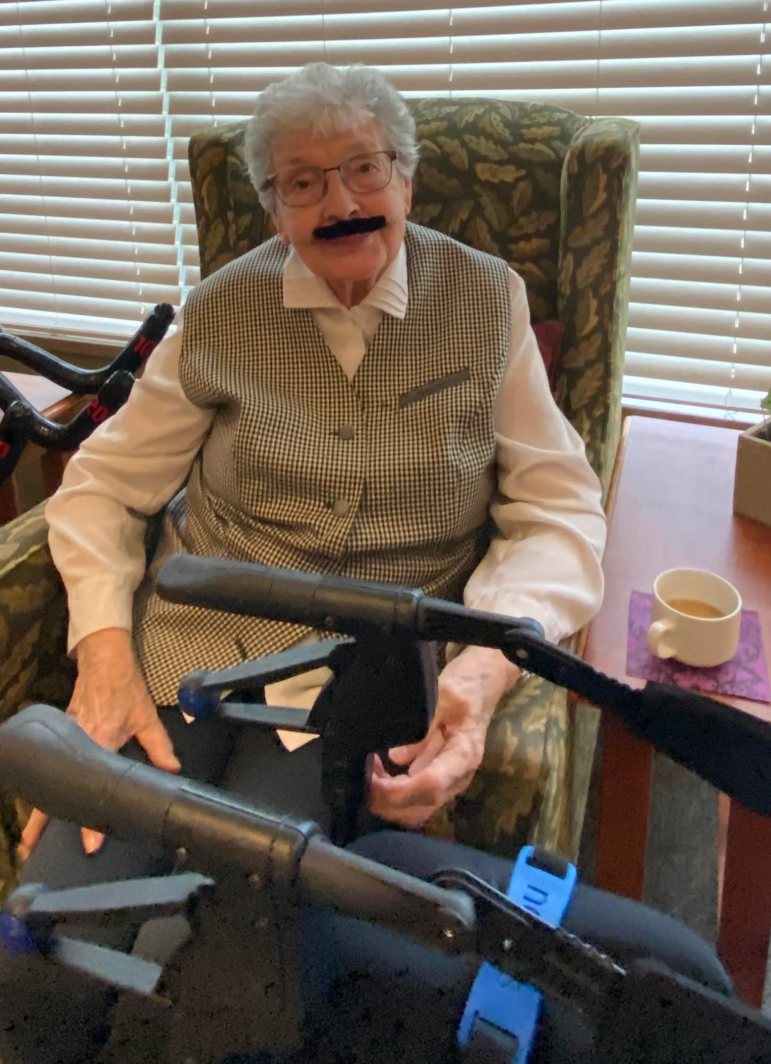 Senior resident sitting in a chair with a playful expression.