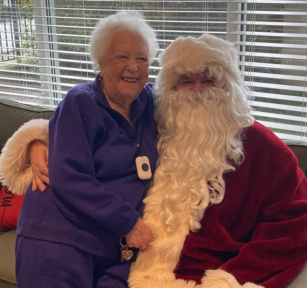 Resident with Santa Claus in a cozy indoor setting.