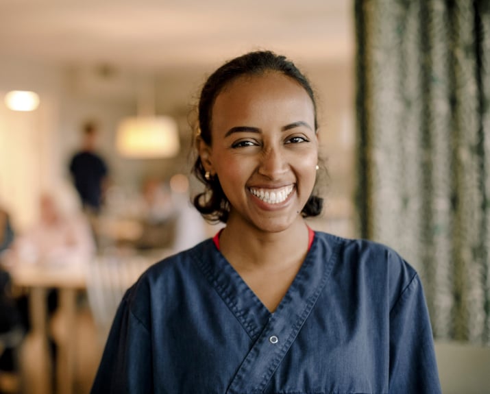 Staff member smiling in a communal dining area.