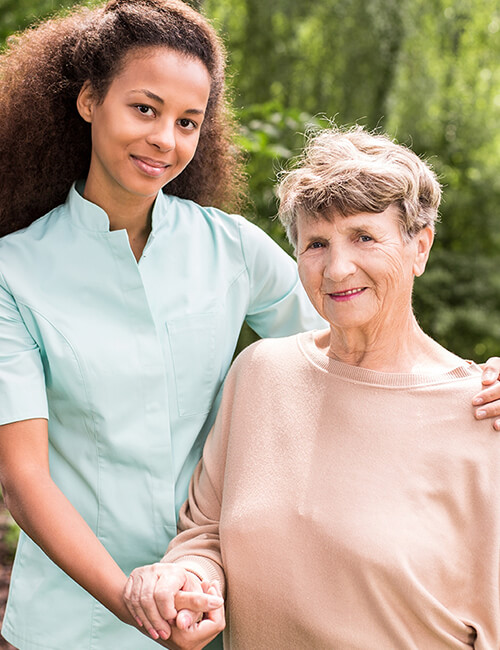 A caregiver with an elderly resident outdoors.