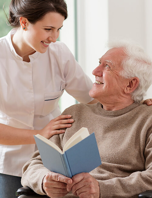 Caregiver interacting with a smiling elderly resident.